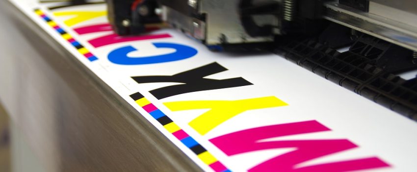 Plotter head printing CMYK test on white paper. Large digital inkjet machine work.